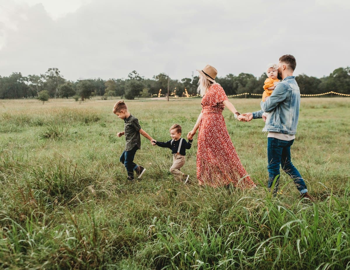 Family of five walking hand in hand through a field